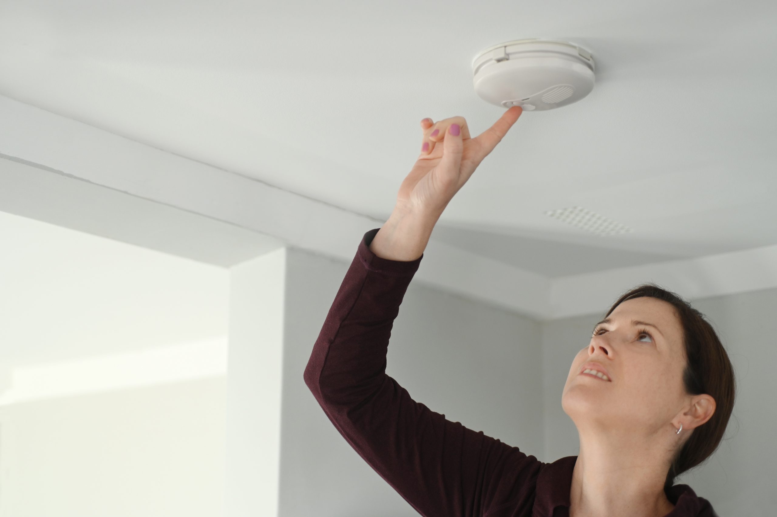 Young adult woman checking fire alarm