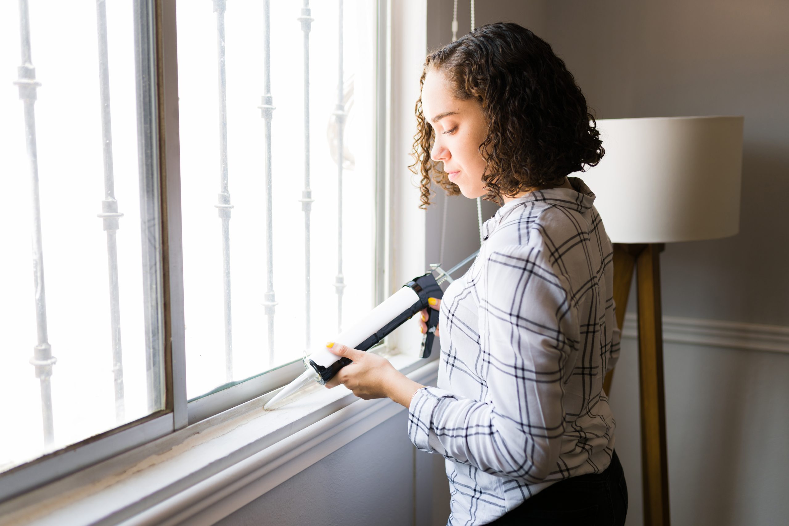Handy woman sealing and repairing her windows